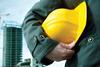 A man holding a hard hat with construction in the background