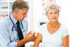 Male GP injecting arm of older woman patient