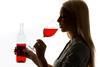 A blonde young woman drinking large glass of red wine