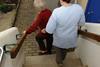 A community nurse helping an older woman down steps