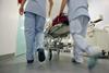 Nurses pushing hospital trolley into hospital corridor