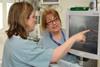 Two female nurses discuss computer readings