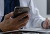 Doctor using mobile smartphone working on laptop computer in medical office Close the teleconference telemedicine