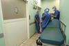 Three nurses in hospital corridor next to dirty bed