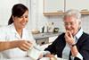A community carer helps an older person with breakfast