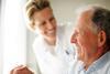 Elderly man in wheelchair with smiling healthcare worker