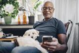 capita-photography-stock-original-getty1151007843-smiling-retired-senior-male-using-smart-phone-while-sitting-with-dog-in-room-at-home (1)