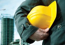 A man holding a hard hat with construction in the background