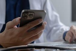 Doctor using mobile smartphone working on laptop computer in medical office Close the teleconference telemedicine