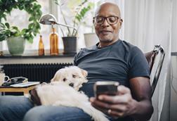 capita-photography-stock-original-getty1151007843-smiling-retired-senior-male-using-smart-phone-while-sitting-with-dog-in-room-at-home (1)