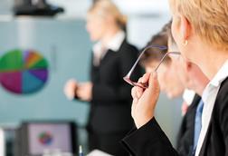 A workshop or meeting room with flip chart and people in suits
