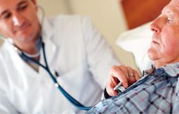 Elderly in man in bed with health worker tending to him