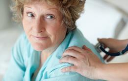 Woman sitting looking up at someone, their hand on her shoulder