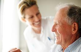 Elderly man in wheelchair with smiling healthcare worker