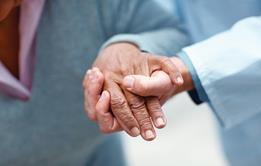 A health professionals hand steadying and elderly womans hand