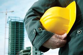 A man holding a hard hat with construction in the background