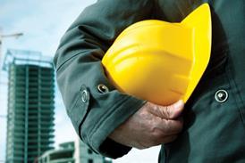 A man holding a hard hat with construction in the background