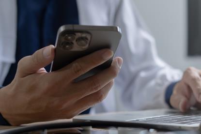 Doctor using mobile smartphone working on laptop computer in medical office Close the teleconference telemedicine