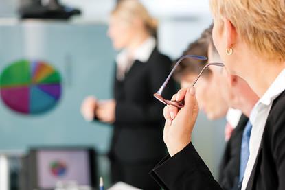 A workshop or meeting room with flip chart and people in suits
