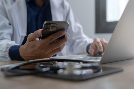 Doctor using mobile smartphone working on laptop computer in medical office Close the teleconference telemedicine