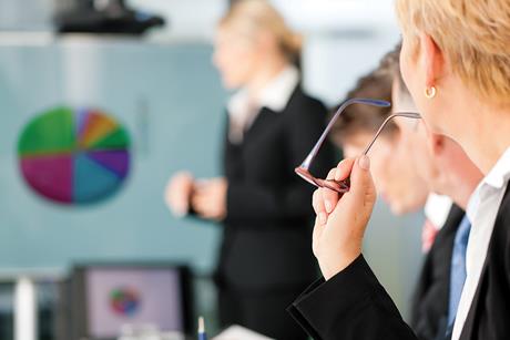 A workshop or meeting room with flip chart and people in suits