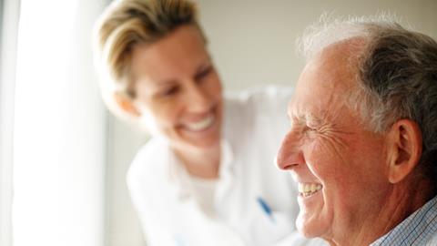 Elderly man in wheelchair with smiling healthcare worker