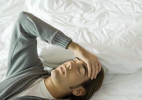 man lying on bed stressed and or tired, self diagnosis: migraine