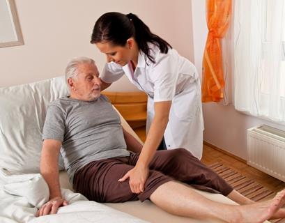 A nurse helping an older man get out of bed