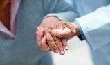 A health professionals hand steadying and elderly womans hand