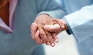 A health professionals hand steadying and elderly womans hand