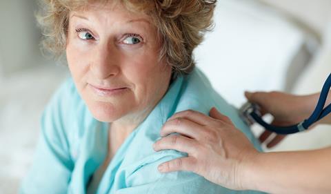 Woman sitting looking up at someone, their hand on her shoulder