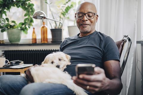 capita-photography-stock-original-getty1151007843-smiling-retired-senior-male-using-smart-phone-while-sitting-with-dog-in-room-at-home (1)