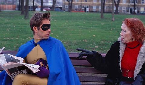 Superhero and woman on park bench