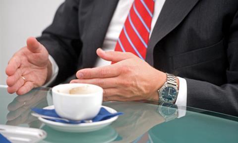 Man at a table, gesticulating as though in conversation