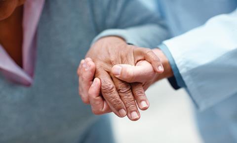 A health professionals hand steadying and elderly womans hand