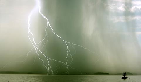 Storm over a lake with lone boatman to the side