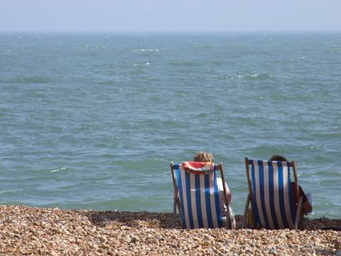 Two people in deckchairs on a beach