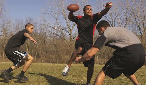 Men playing American football in park