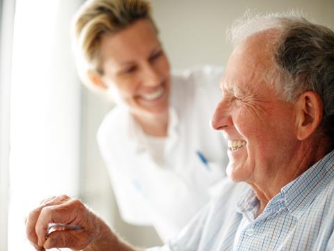Elderly man in wheelchair with smiling healthcare worker